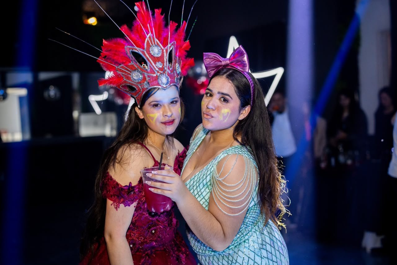 Dos invitadas posando con cotillón de plumas y vinchas en la pista