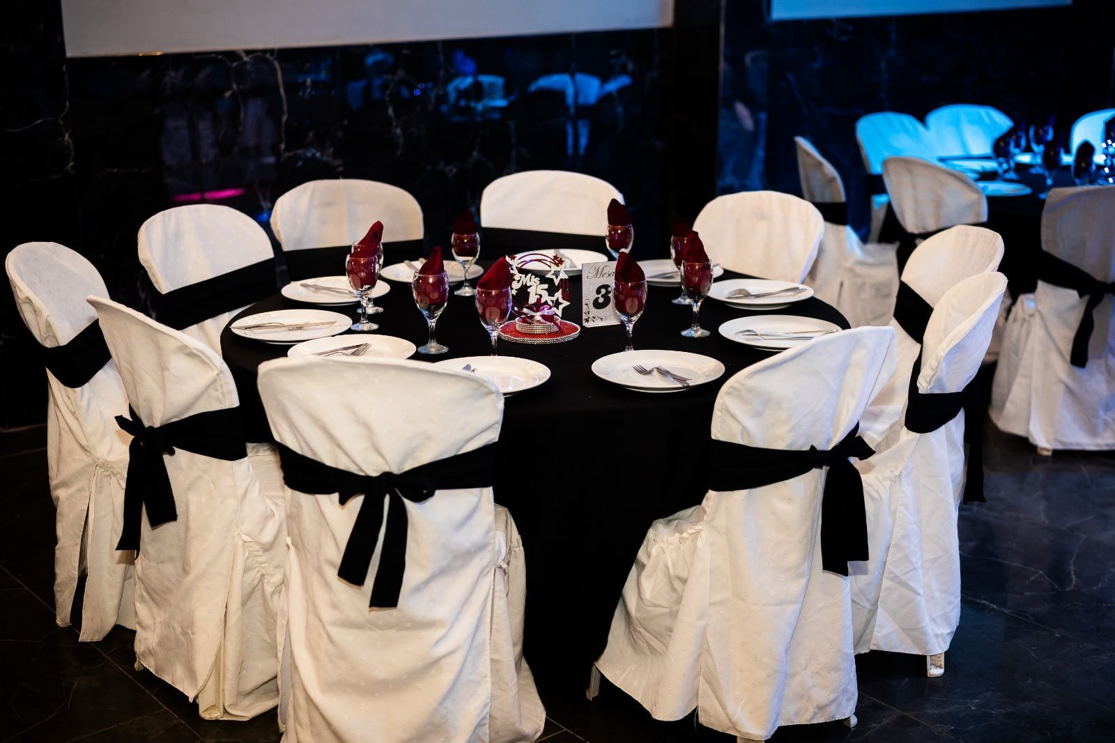 Cubre sillas blancos con lazos negros alrededor de la mesa